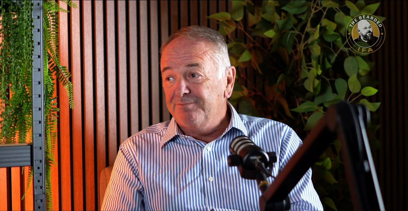 A guest on camera in the studio, framed against slatted walls and greenery